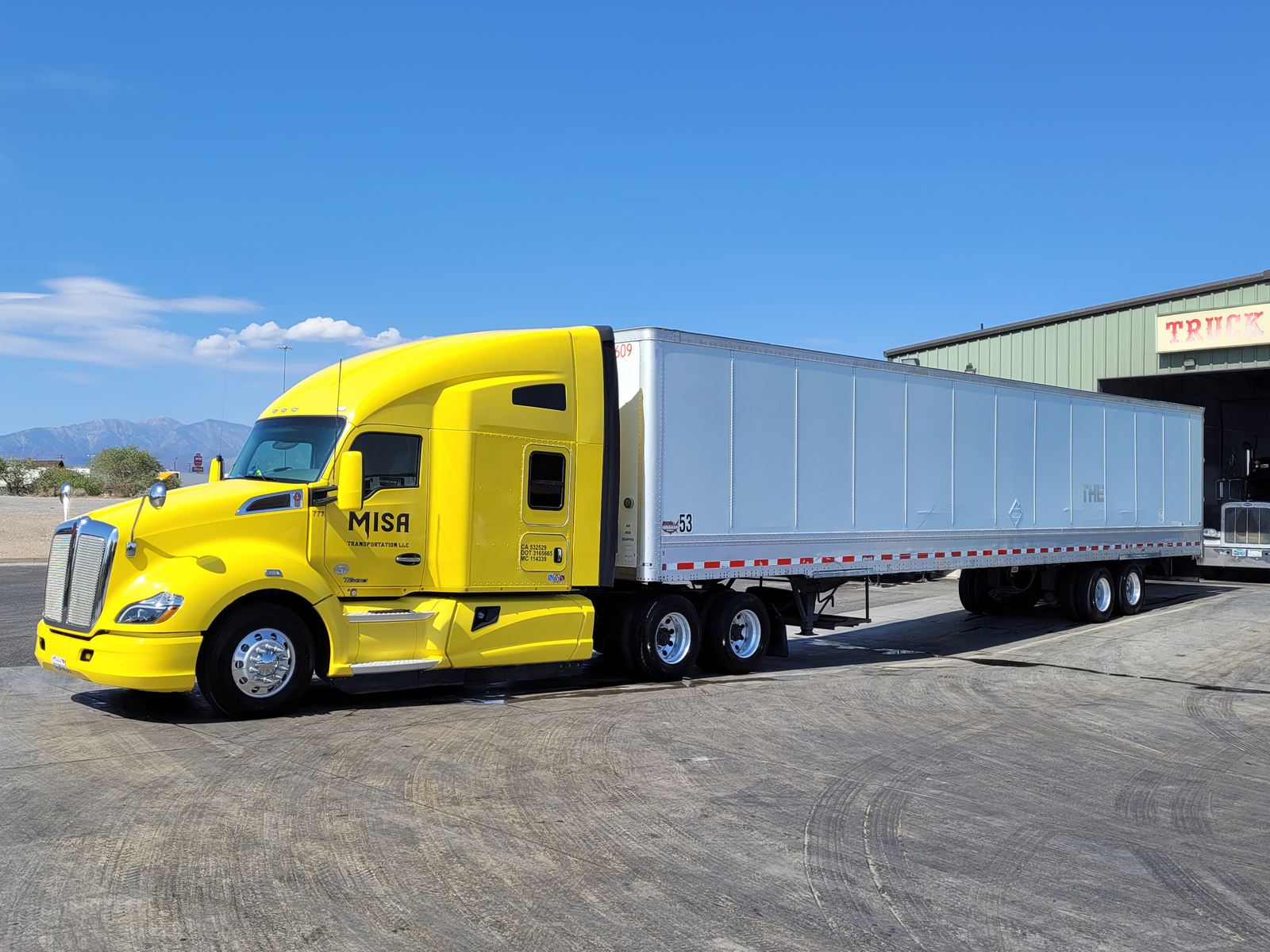 Misa Transportation yellow Kenworth tractor with white dry van trailer in daylight